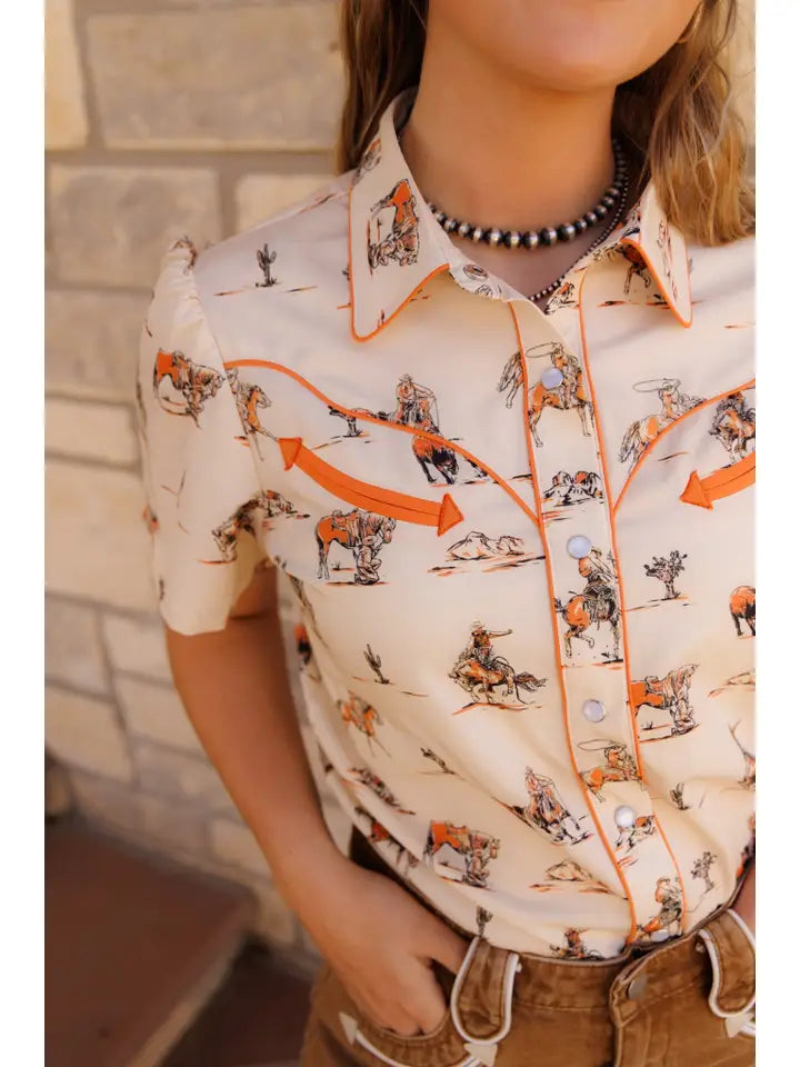 Person wearing a patterned shirt with cowboys and horses design.
