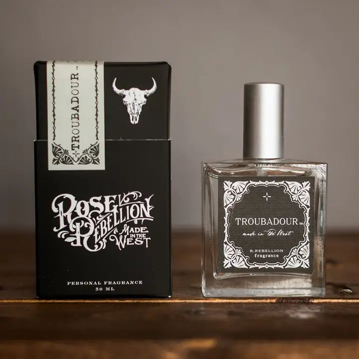 Perfume bottle and packaging of 'Troubadour' by Rose Rebellion on a wooden surface.