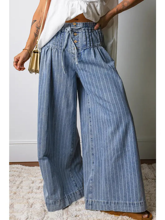 Person wearing blue striped wide-leg jeans with a white top and gold handbag.