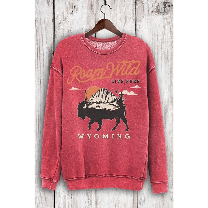 Red sweatshirt with 'Roam Wild Live Free Wyoming' text and bison graphic on a wooden background