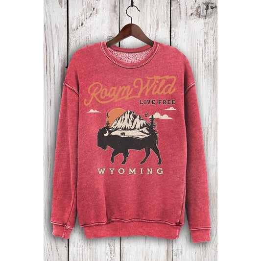 Red sweatshirt with 'Roam Wild Live Free Wyoming' text and bison graphic on a wooden background
