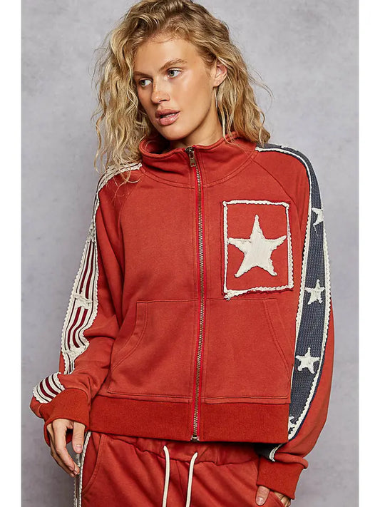 Person wearing a red track suit with a white star, blue stripe and red and white stripes and stars on the sleeves.