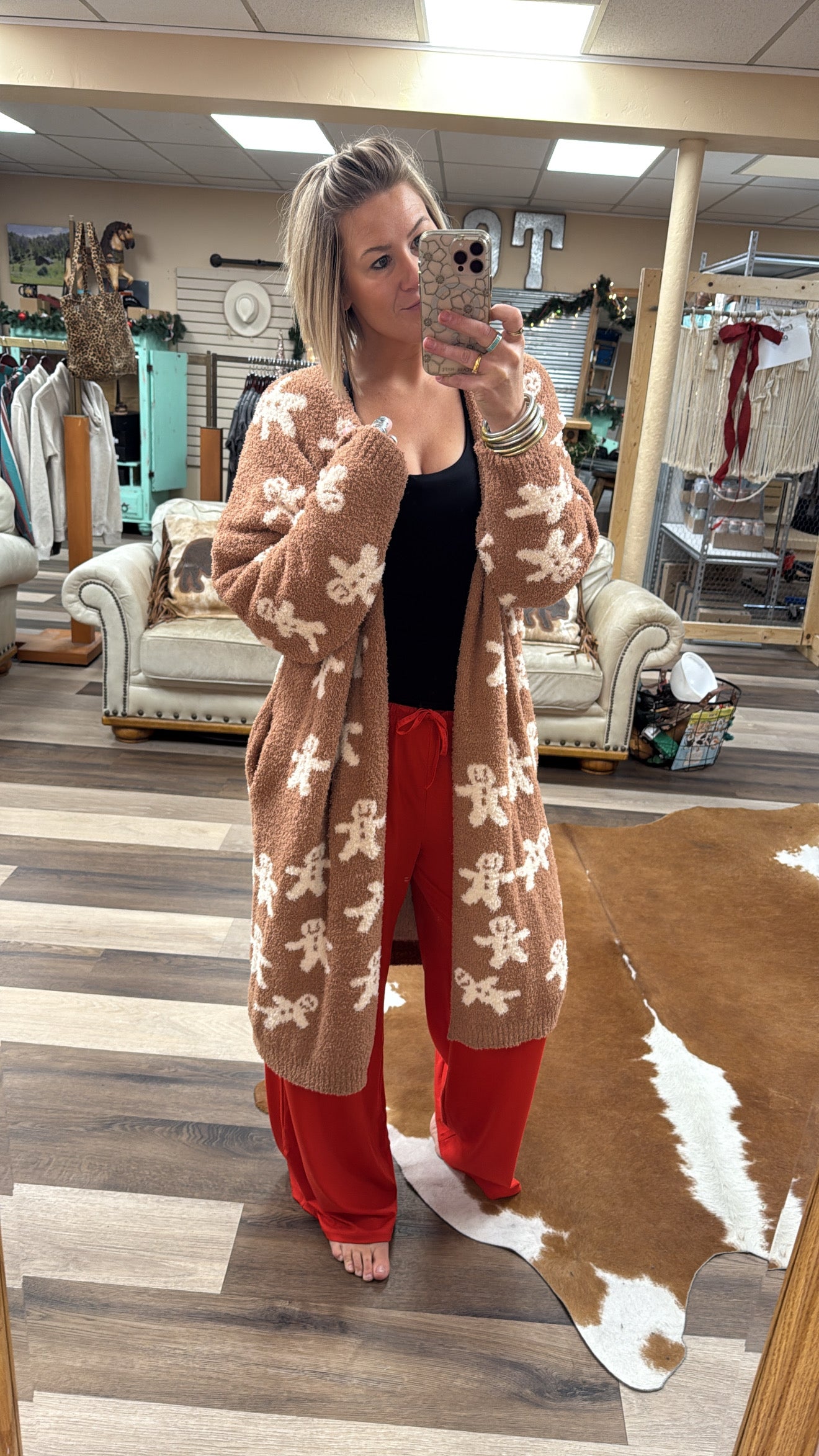 Person wearing a patterned cardigan and red pants in a store setting