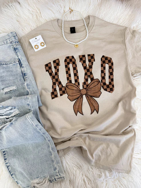 Beige t-shirt with checkered 'XOXO' design and bow. 