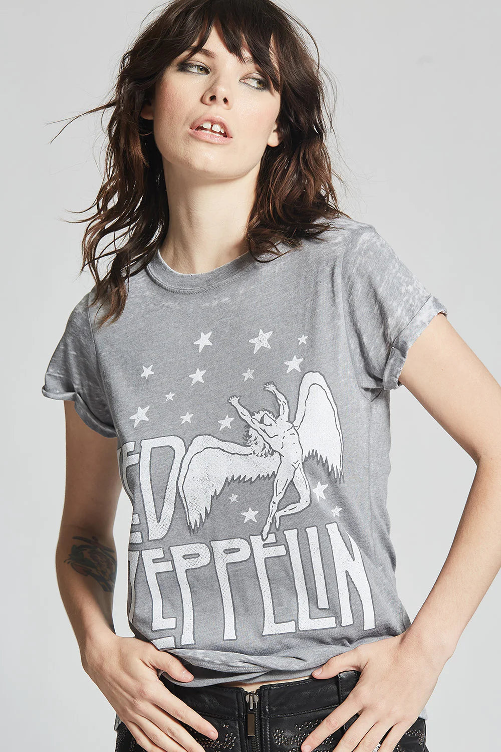 Person wearing a gray t-shirt with 'Led Zeppelin' graphic design on a plain background