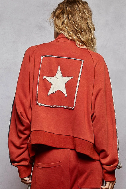 Person wearing a red jacket with a white star on the back against a gray background. 
