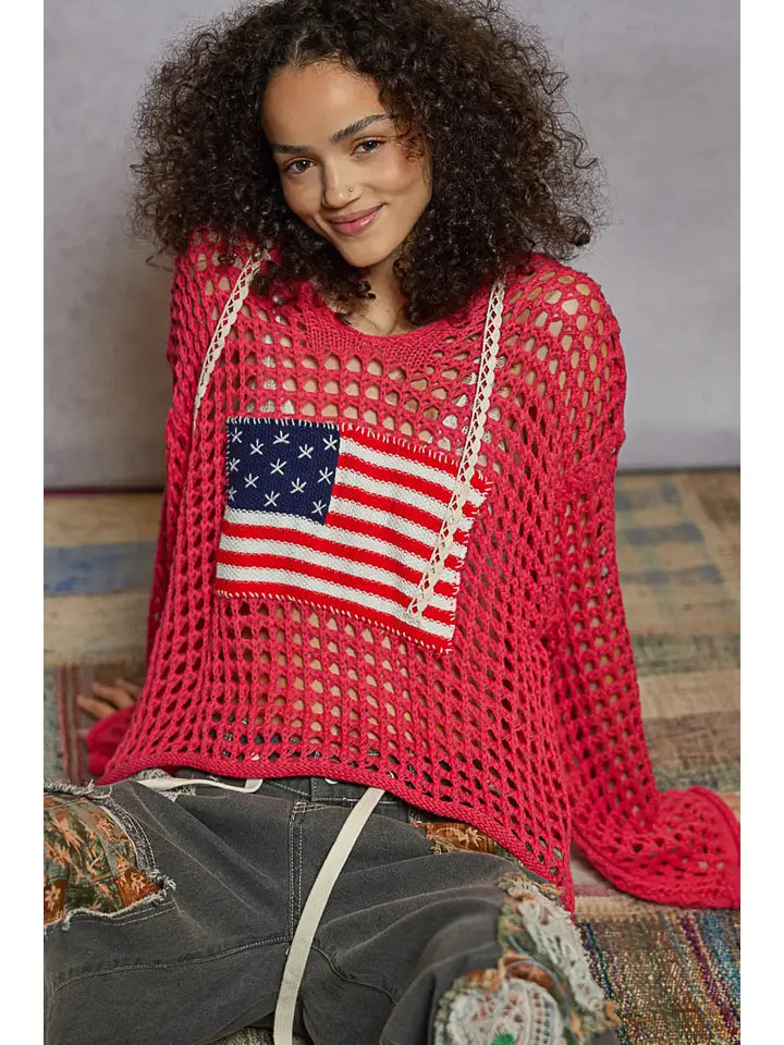 Person wearing a red knit sweater with an American flag patch.