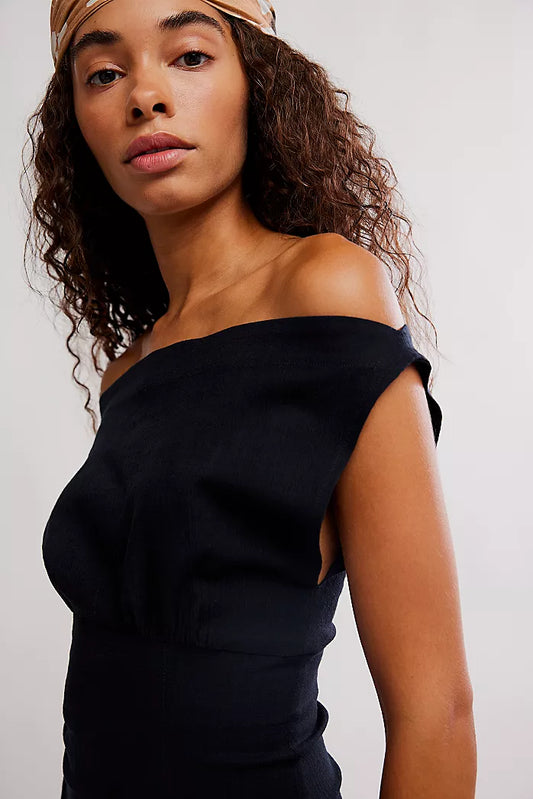 Woman wearing a black off-shoulder top against a plain background